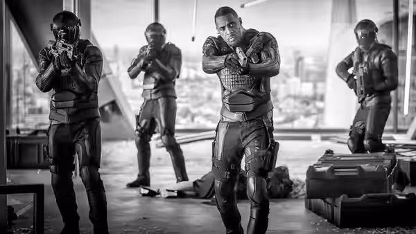 Brixton (Idris Elba) leads armed soldiers through a bright office