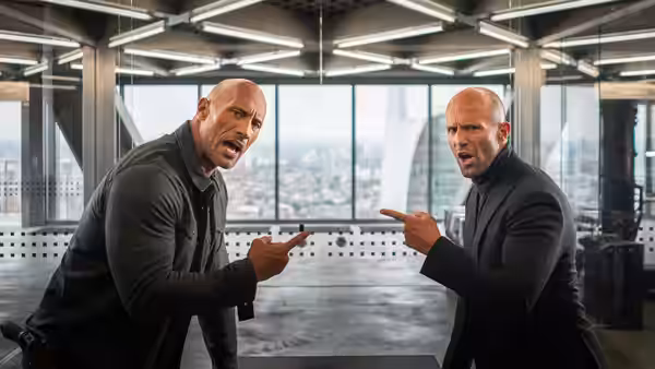 Luke Hobbs (Dwayne Johnson) and Deckard Shaw (Jason Statham) point at each other in an office
