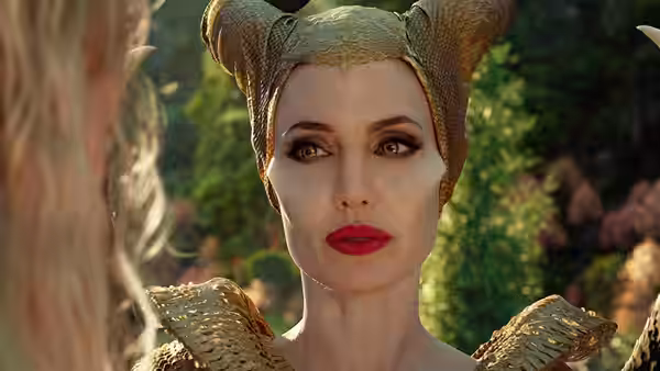 Maleficent (Angelina Jolie) gazes at someone just beyond the frame in a forest