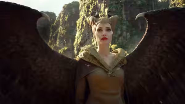 Maleficent (Angelina Jolie) stands with outstretched wings among rocky cliffs