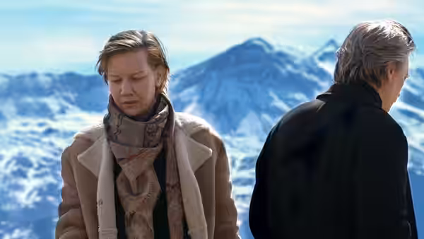 Sandra Voyter stands before snowy mountains with a man beside her