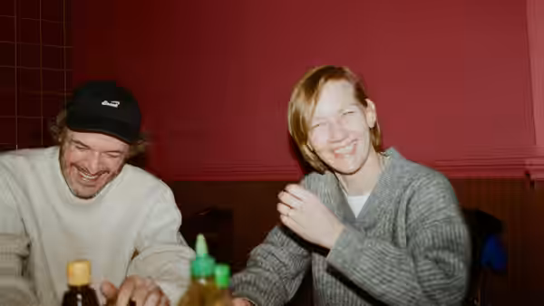 A smiling man and woman sit together at a table with bottles