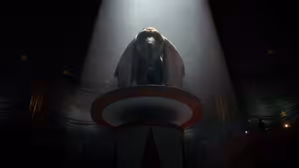 Dumbo stands atop a circus platform beneath a spotlight