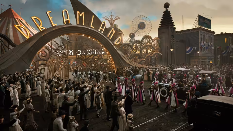 A crowd gathers outside Dreamland as performers parade beneath the amusement park entrance