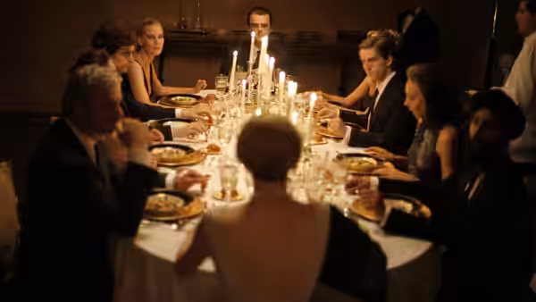 The Recchi family gathers around a candlelit dining table in a dark formal room