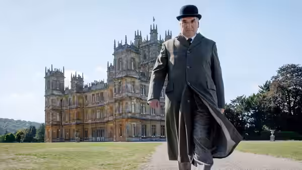 Robert Crawley (Hugh Bonneville) walks across the grounds toward Downton Abbey