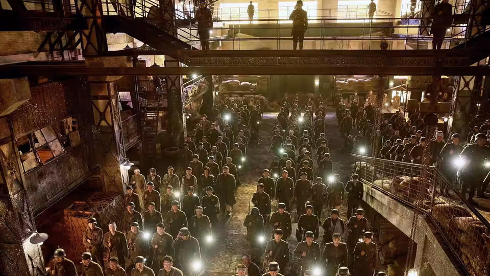 Chinese soldiers crowd a dim warehouse beneath a lone figure on an overhead walkway