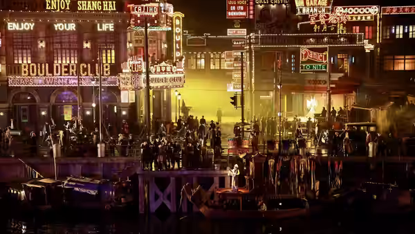 Crowds gather on Shanghai waterfront platforms beneath neon signs and smoky firelight