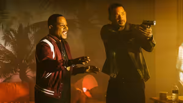 Marcus (Martin Lawrence) gestures beside Mike (Will Smith), who aims a pistol indoors
