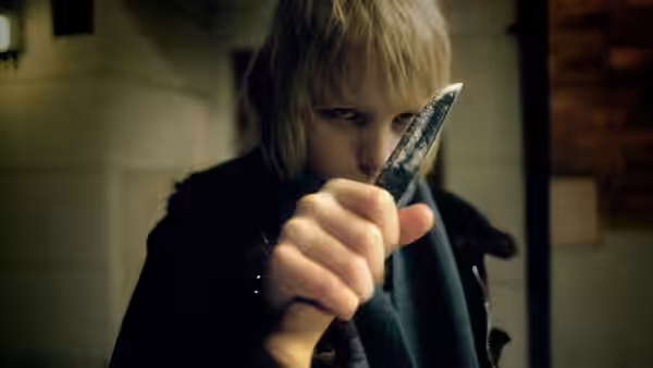 Oskar (Kåre Hedebrant) holding a knife toward the viewer