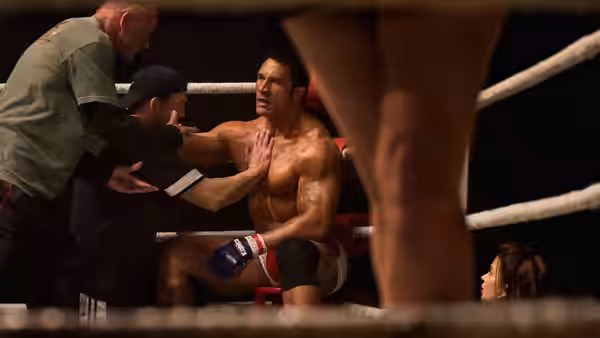 Mark Kerr (Dwayne Johnson) sits in the ring corner receiving advice from two men