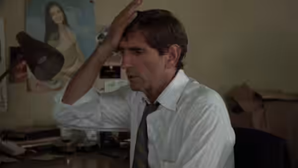 Bud (Harry Dean Stanton) clutches his head in a messy office