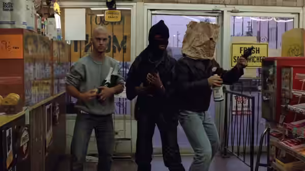 Three masked men brandish guns inside a brightly lit convenience store