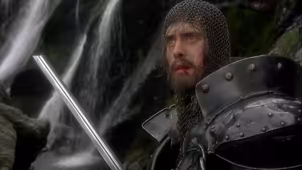 a wounded knight in chainmail holds his sword before a waterfall