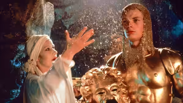 Morgana gestures with an open hand beside a knight in golden armor