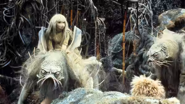 Kira rides a Landstrider through the forest as Fizzgig watches nearby