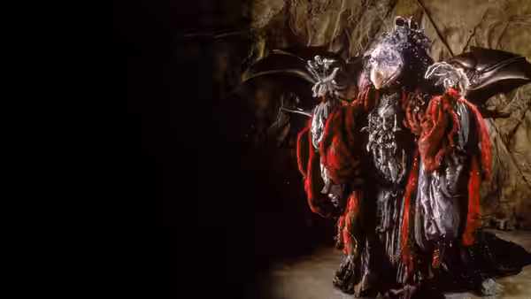 Two Skeksis in red robes stand inside a dark cavern