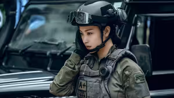 A woman in police bomb squad gear stands beside an armoured vehicle