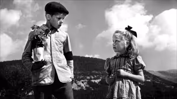 Michel Dolle (Georges Poujouly), holding flowers, looks at Paulette (Brigitte Fossey) in the hills
