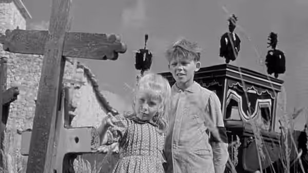 Paulette (Brigitte Fossey) and Michel Dolle (Georges Poujouly) stand among wooden crosses in a cemetery