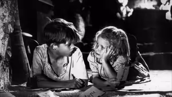 Michel Dolle (Georges Poujouly) and Paulette (Brigitte Fossey) lean together over a table indoors