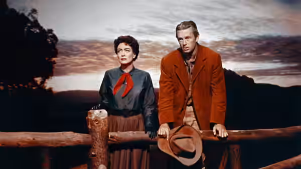 Vienna (Joan Crawford) and Johnny (Sterling Hayden) lean against a wooden railing outdoors