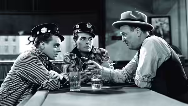 Three men gather around a table as one reaches toward the drinks