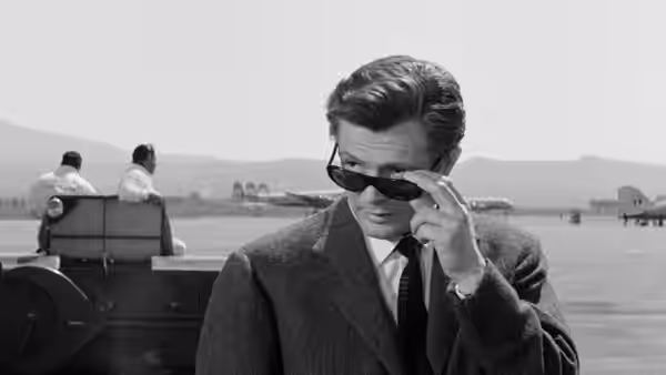 Marcello Rubini (Marcello Mastroianni) lowers his sunglasses beside a car at the waterfront