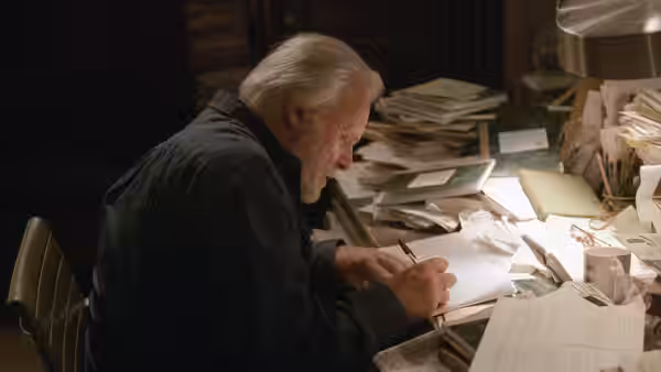 Robert (Anthony Hopkins) writes at a desk covered with papers