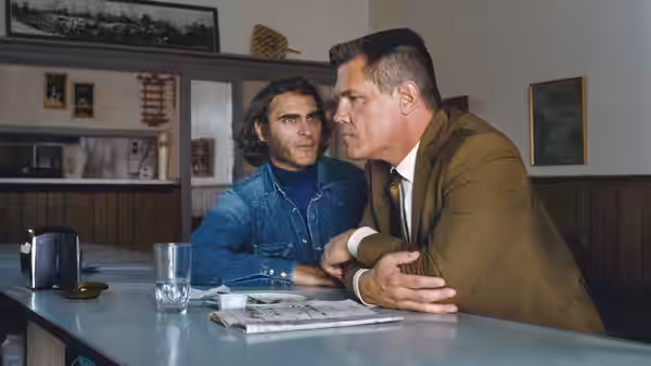 Doc Sportello (Joaquin Phoenix) sits across a diner counter from a uniformed police detective