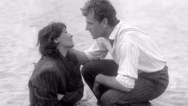 Gino Costa (Massimo Girotti) crouches beside Giovanna Bragana (Clara Calamai) outdoors