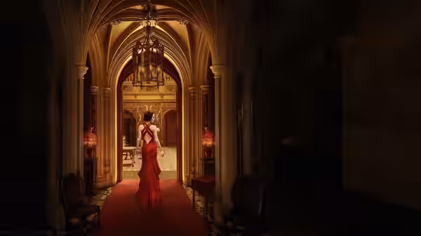 Woman in red gown walking down a carpeted arched corridor