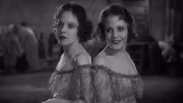 The Siamese twin sisters stand back to back in a dressing room