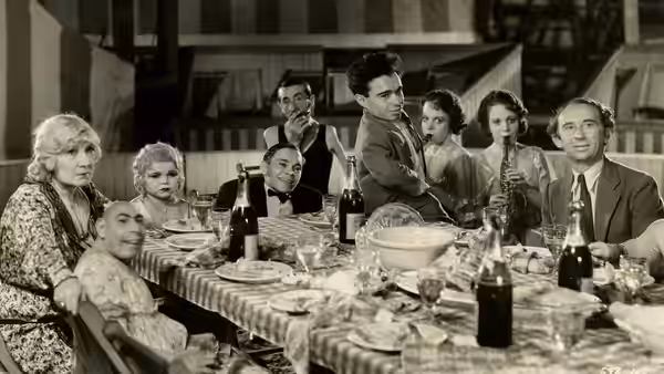 A group of diners gathers around a long table laden with food and bottles