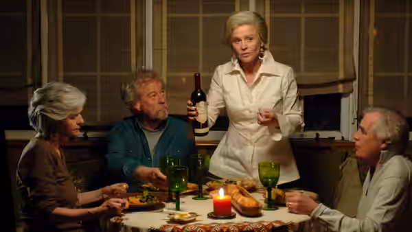 Marian (Olympia Dukakis) serves wine as Fiona, Grant and Aubrey sit around the dinner table