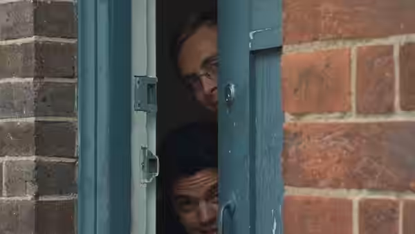 Two students peer through a partly opened blue door