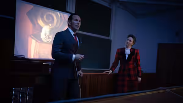 Ed Warren (Patrick Wilson) holding a remote while Lorraine Warren (Vera Farmiga) stands nearby