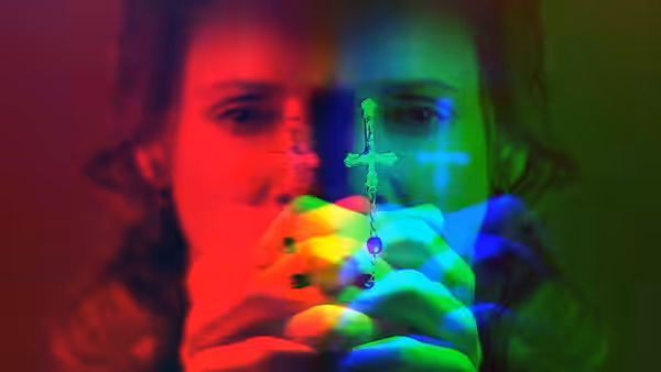 Young woman holding two glowing crosses in front of her face