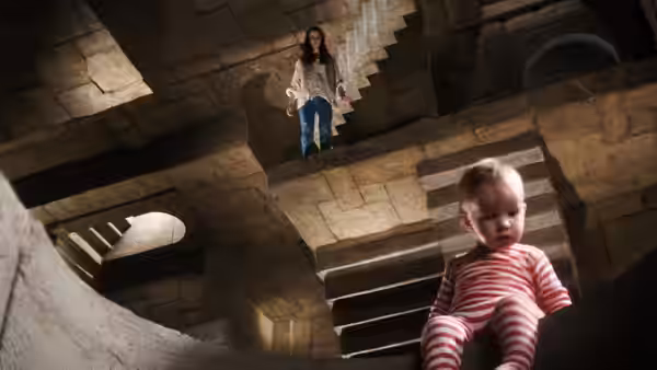 Sarah (Jennifer Connelly) on a ledge above Toby (Toby Froud) on stairs