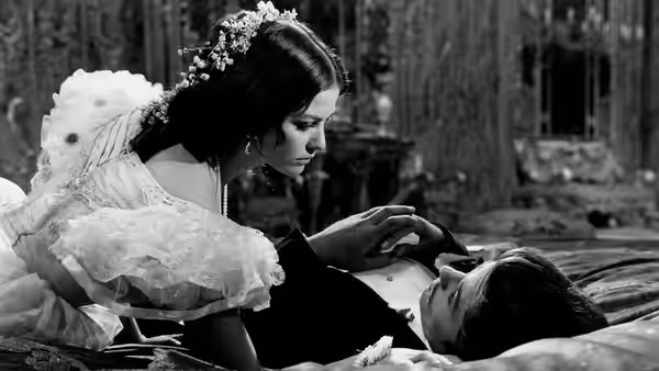 Angelica (Claudia Cardinale) leans over Tancredi (Alain Delon), who lies on a bed