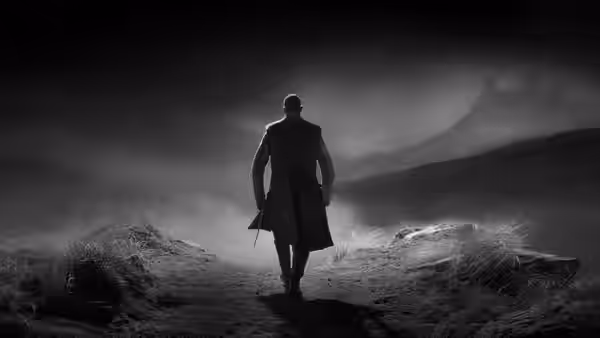 a man in a long coat walking along a misty path towards ruins