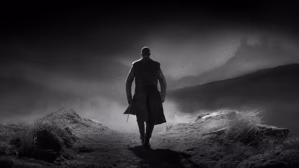 a man in a long coat walking along a misty path towards ruins