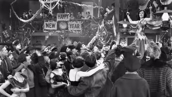 A woman dances on a raised platform as a crowd celebrates beneath New Year decorations