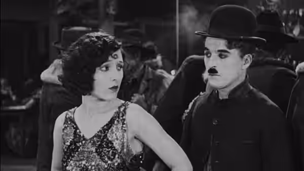 The Lone Prospector (Charlie Chaplin) stands beside a woman in a sequined dress at a dance hall