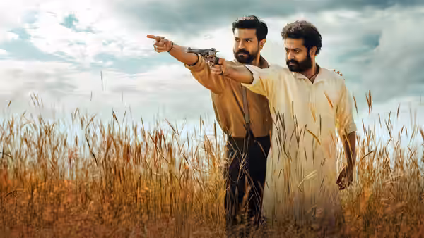 Alluri Sitarama Raju (Ram Charan) aims a gun as Komaram Bheem (N.T. Rama Rao Jr.) points across a field