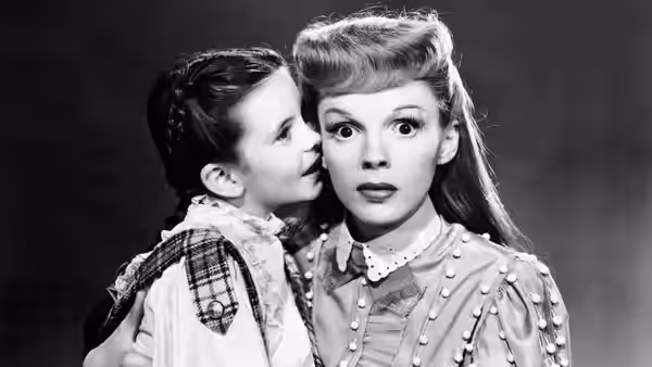 Tootie Smith (Margaret O'Brien) whispers into Esther Smith's (Judy Garland) ear