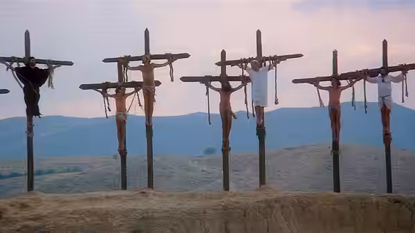 Row of crucified men on crosses overlooks a desert landscape at dusk
