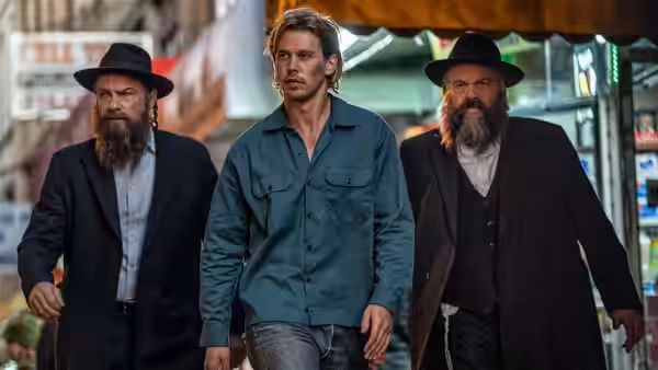 Hank Thompson (Austin Butler) walking between two bearded men in hats