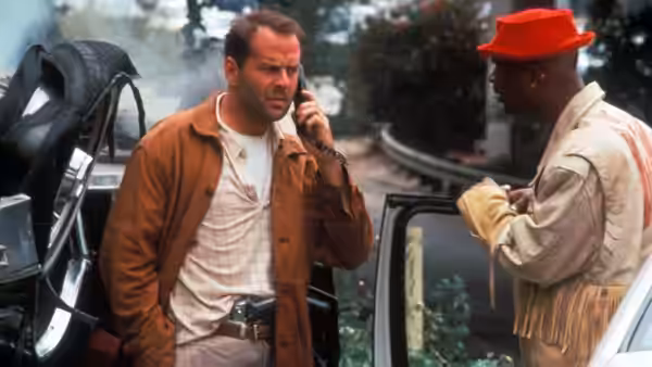 Joe Hallenbeck (Bruce Willis) talks on a phone beside a man in a red hat