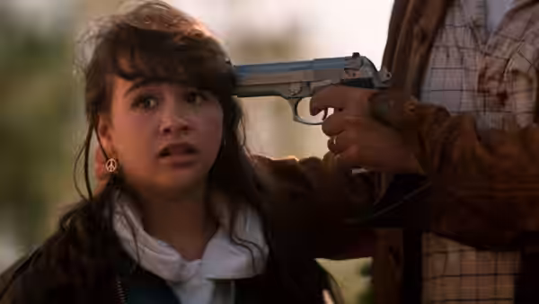 A girl looks alarmed as a man holds a handgun to her head